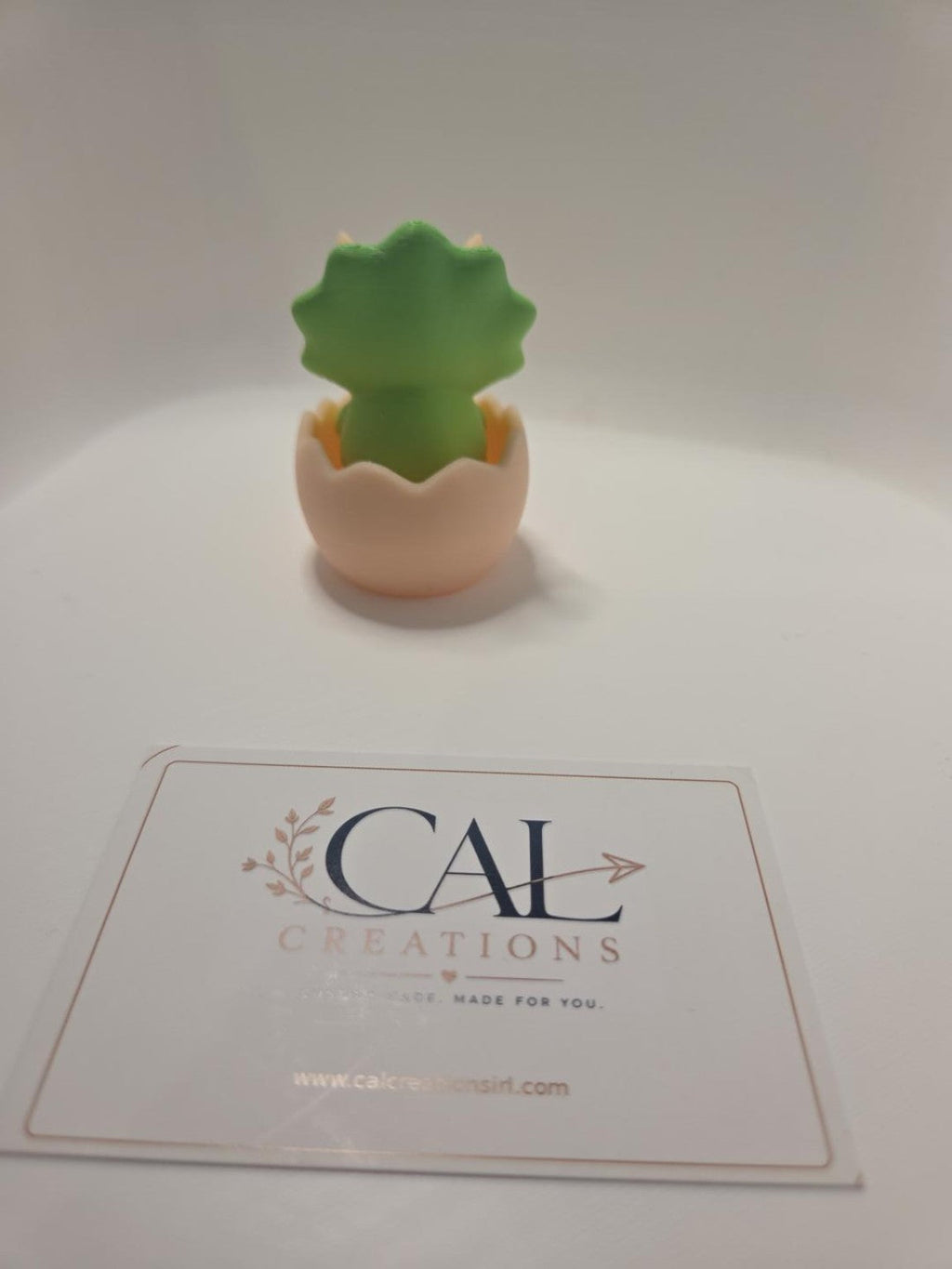 Rear view of green baby triceratops clicker in beige eggshell