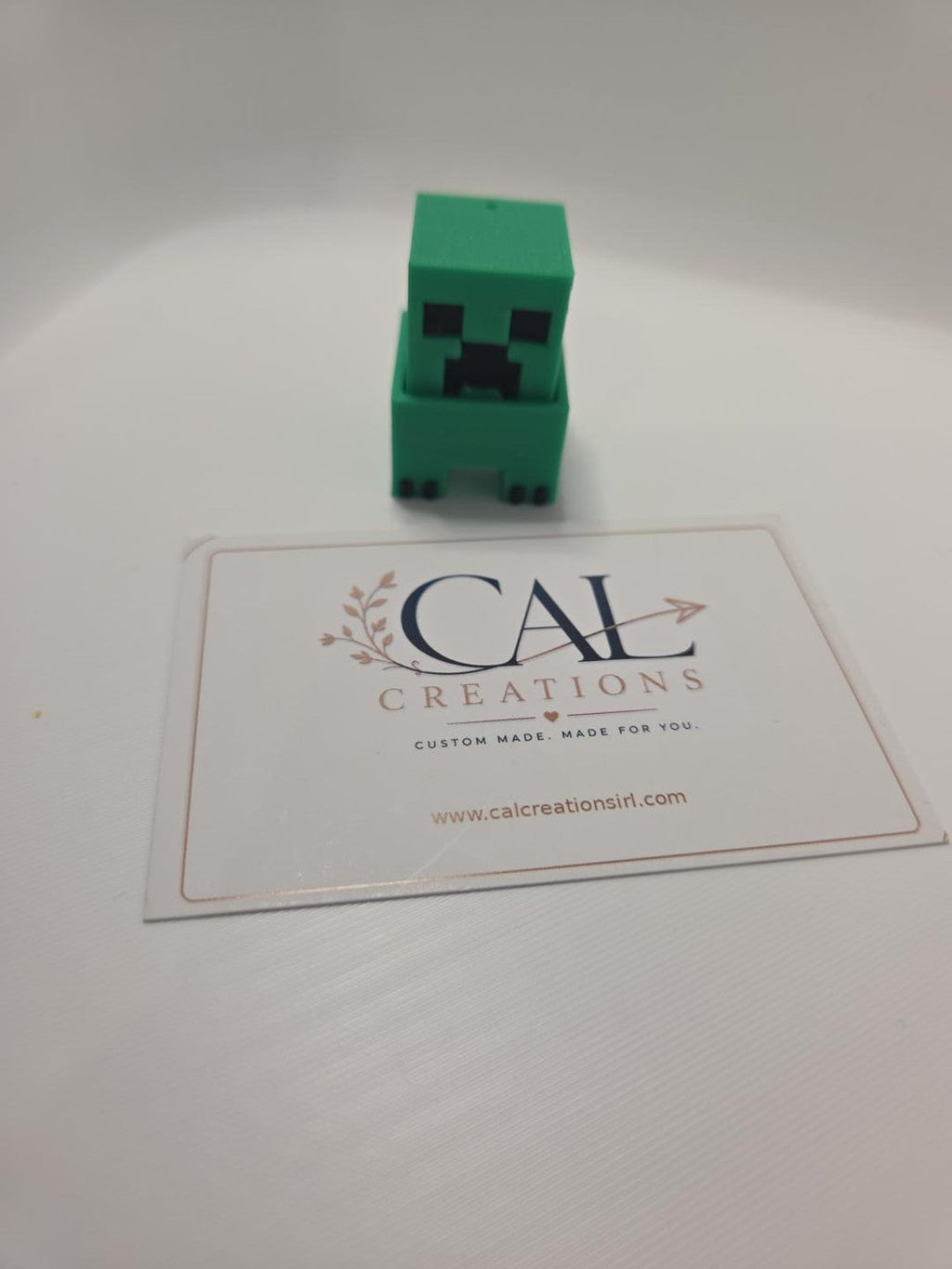 Front view of green pixel-style Creeper clicker with CalCreations branding