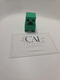 Front view of green pixel-style Creeper clicker with CalCreations branding