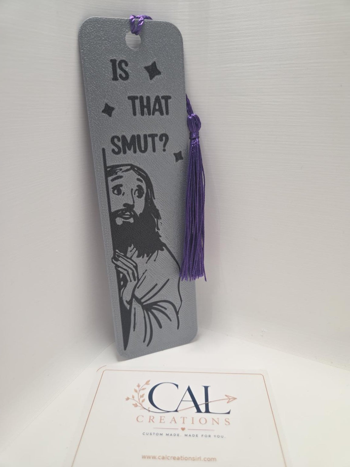Grey and black Is That Smut bookmark with purple tassel, detail view