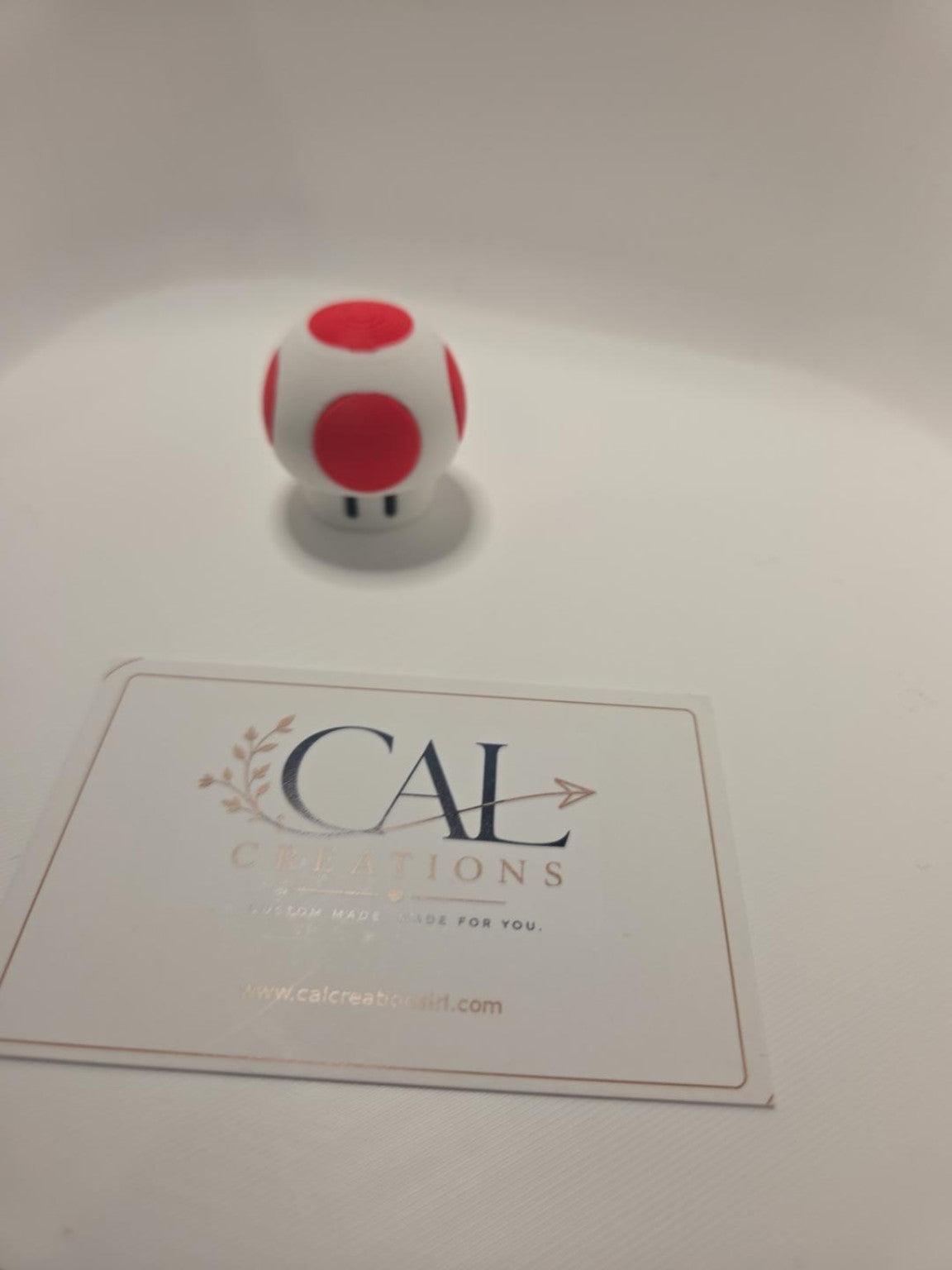 Front view of finished red and white mushroom clicker with CalCreations branding