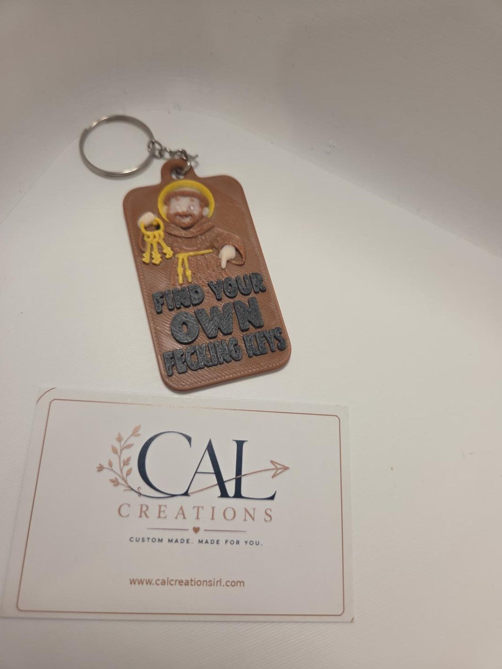 St Anthony keyring in brown with yellow halo and keys, raised black lettering and metal key ring