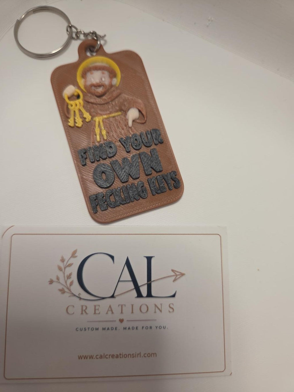 Close-up of St Anthony funny keyring reading Find Your Own Fecking Keys
