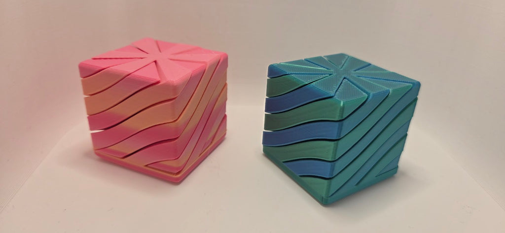 Two 3D printed Infinity Cube fidgets in pink and yellow and blue and green